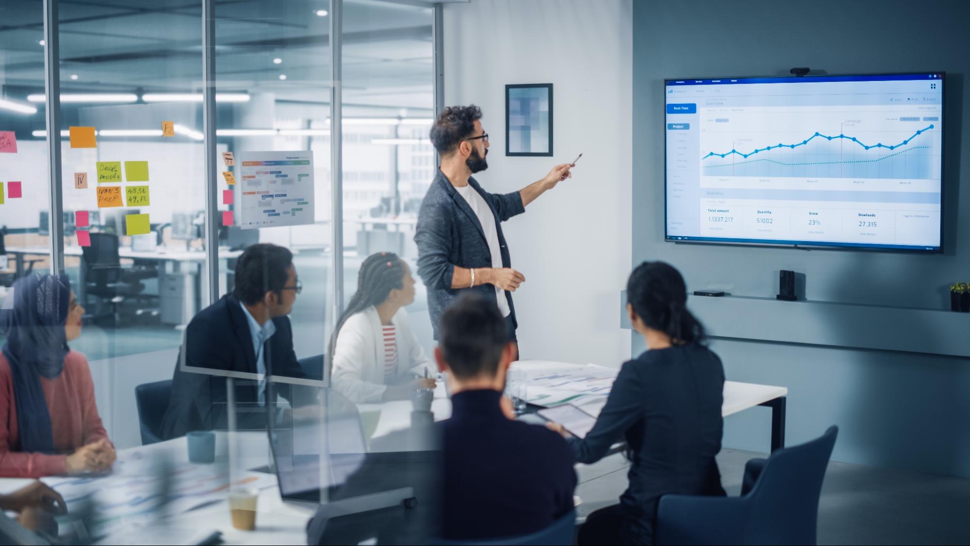 Person in meeting pointing to the data chart